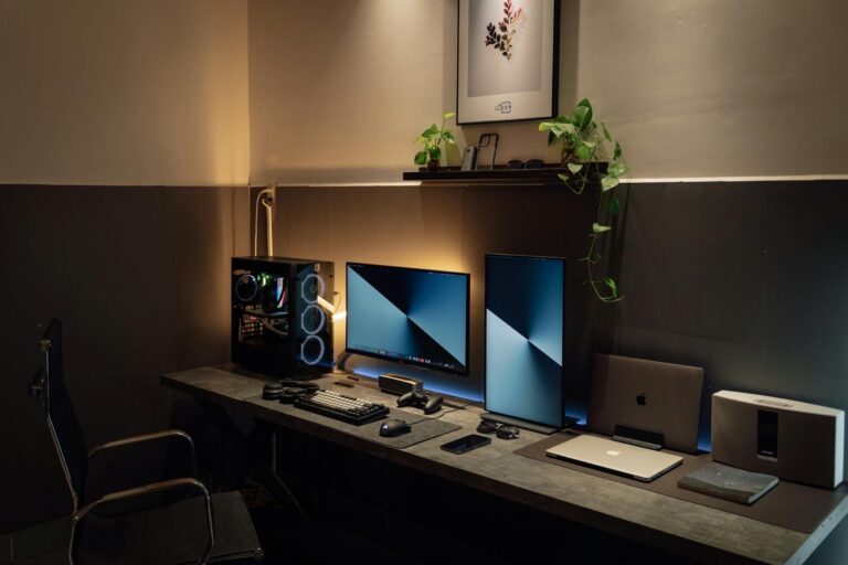 A sleek and modern desk setup featuring dual monitors, gaming PC, and tech gadgets in a well-lit room.
